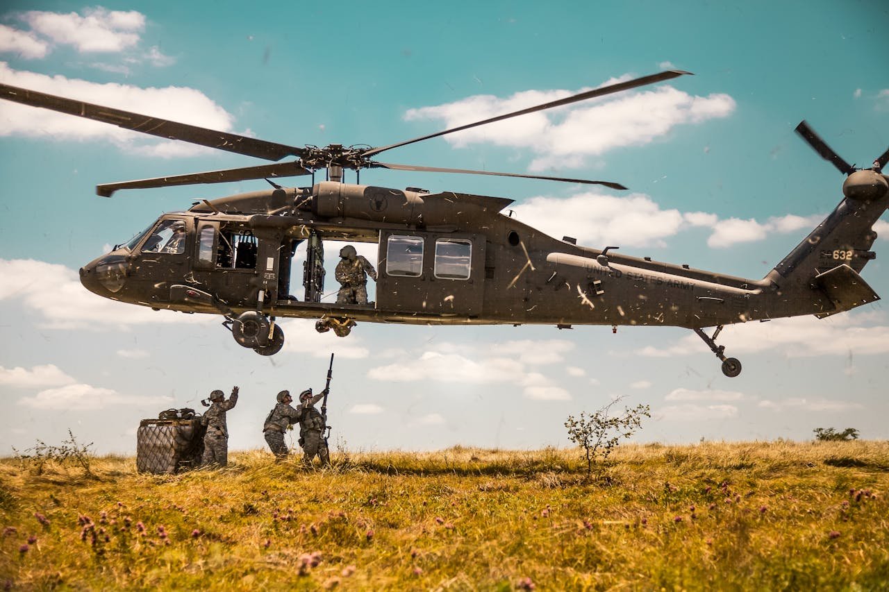A Blackhawk helicopter in a military training mission with soldiers on a field.